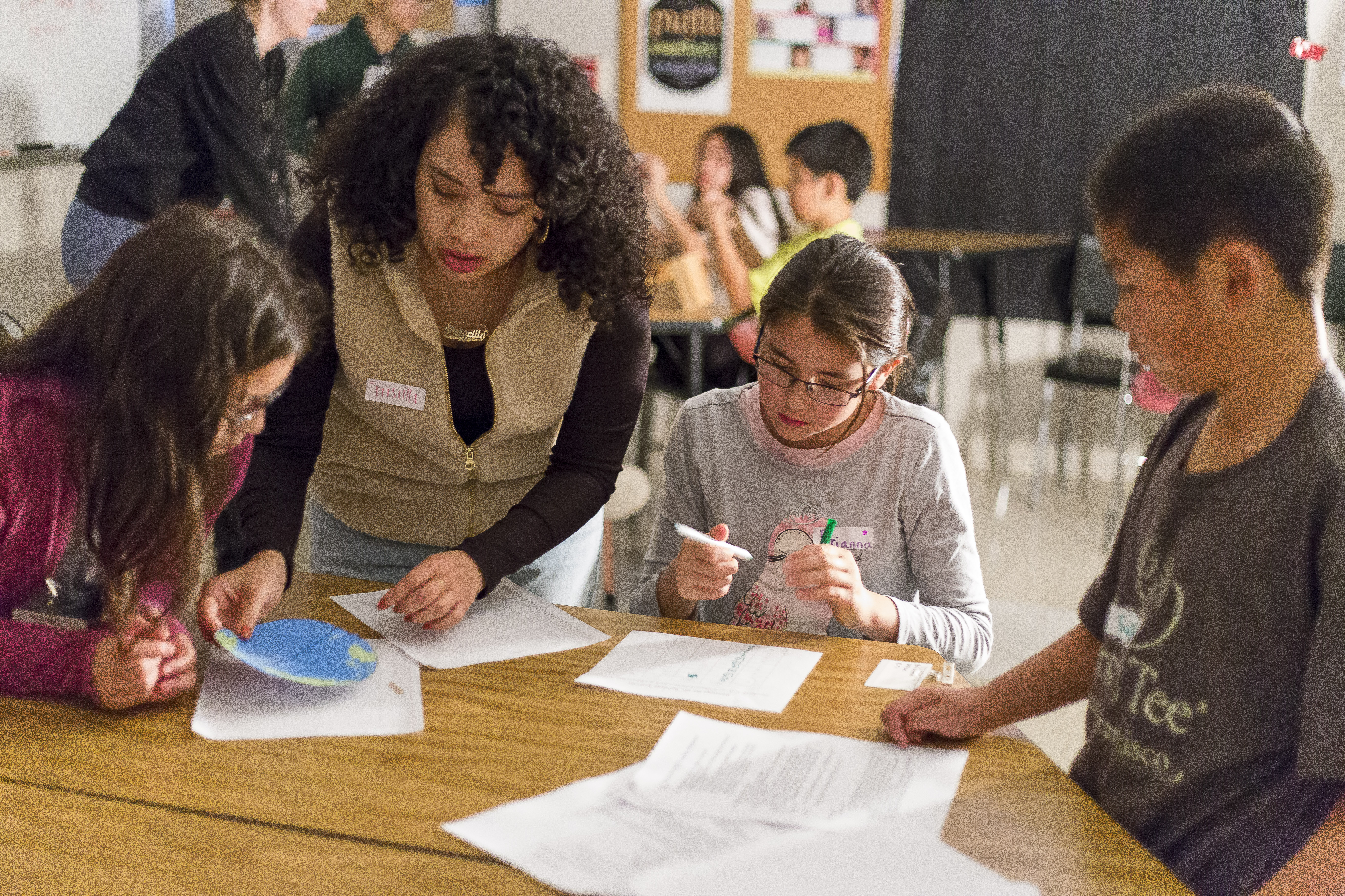 Photo of an adult and three children around a table in a school setting