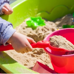 Child with shovel and bucket in a sand box