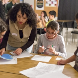 Photo of an adult and three children around a table in a school setting