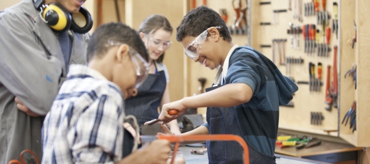 Photo of an adult with children in a woodshop setting