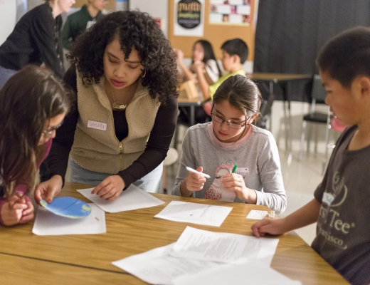 Photo of an adult and three children around a table in a school setting