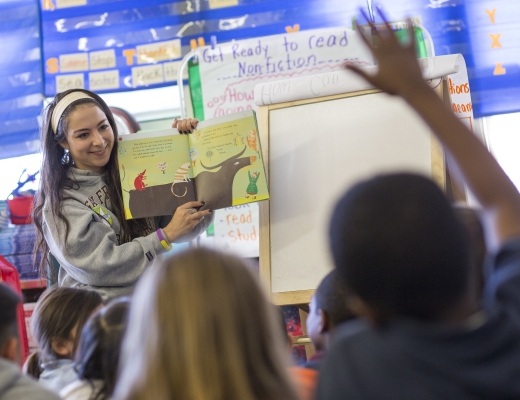 Adult showing an open book to children in a classroom